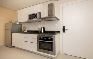 Una cocina moderna con electrodomésticos de acero inoxidable, armarios blancos y salpicadero de azulejos.