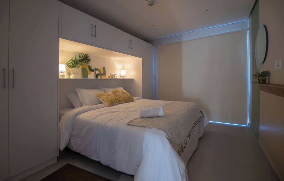 A modern bedroom with a bed, built-in shelving, and a bedside table.