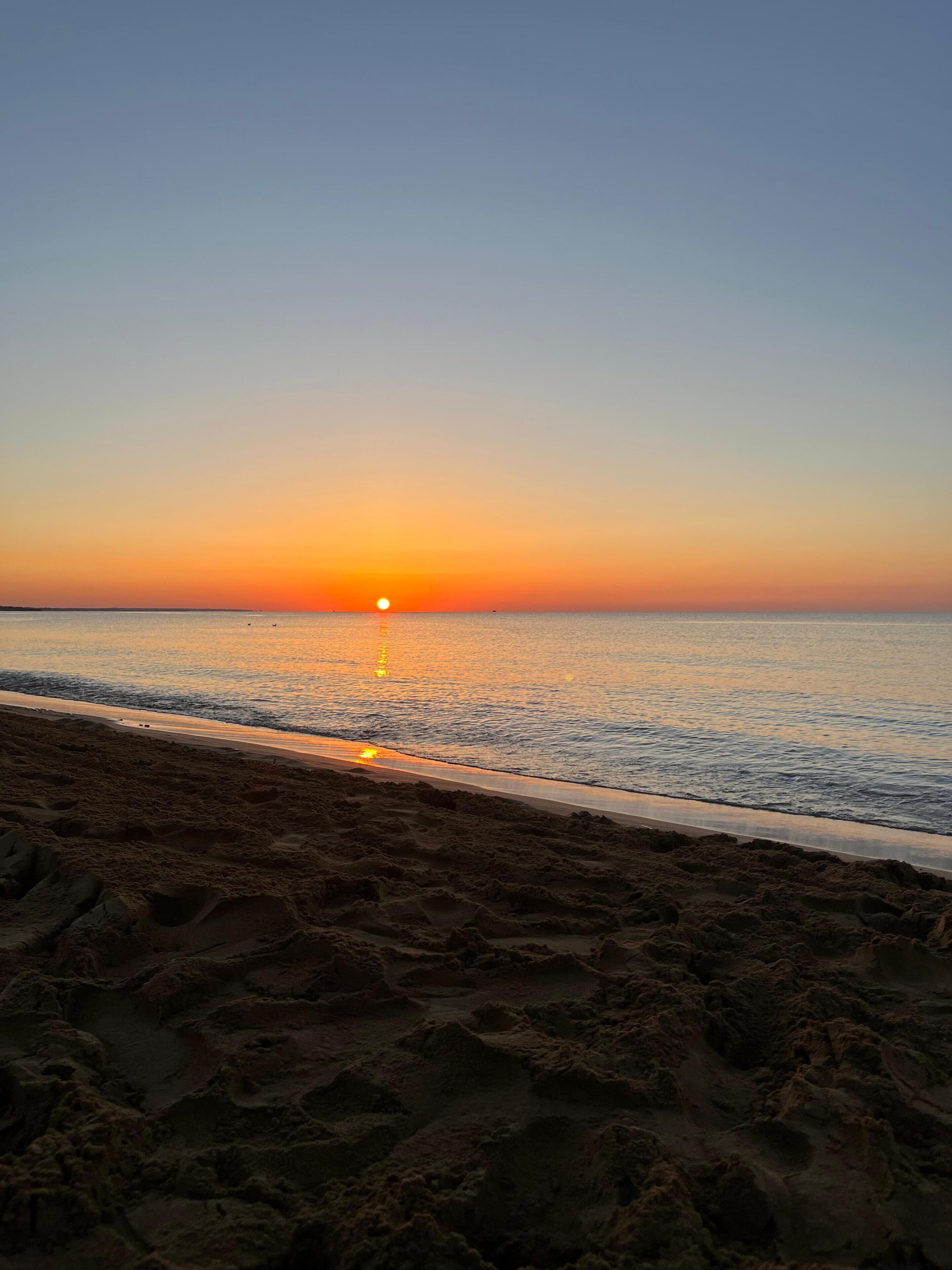Una spiaggia al tramonto con cielo sereno e mare calmo.