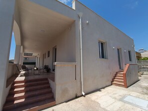 A modern building with a covered outdoor area, a staircase, and a seating arrangement. - Vacation Home 300 m from the Sea, Ideal for Those Seeking Relaxation, Privacy, and Comfort (Avola)