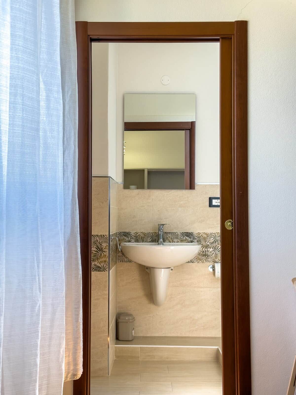 Un baño con lavamanos, espejo y ducha.