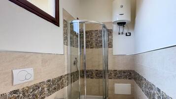Ein Badezimmer mit Duschkabine, zwei Toiletten, einem Bidet und einem Handtuchhalter.