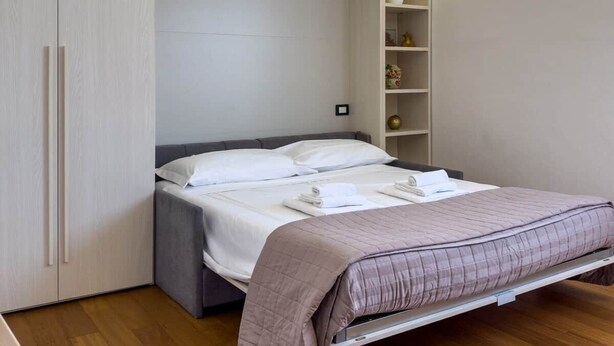Quarto com cama, guarda-roupa, estante e ar condicionado.