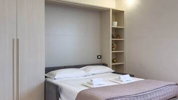Ein Schlafzimmer mit einem Bett, einem Kleiderschrank, einer Regaleinheit und einer Klimaanlage.
