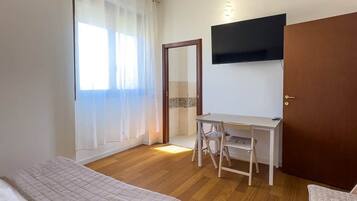 Ein Hotelzimmer mit Bett, Schreibtisch, Stuhl, Fernseher und einer Tür.