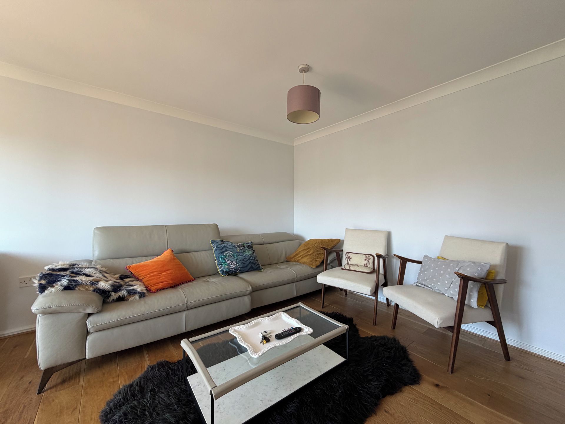 A modern living room with a grey sofa, two armchairs, a coffee table, and a black furry rug.