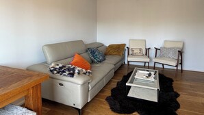 Ein Wohnzimmer mit einer Couch, zwei Sesseln, einem Couchtisch und einem Teppich.