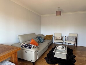 Ein Wohnzimmer mit einer Couch, zwei Sesseln, einem Couchtisch und einem Teppich.