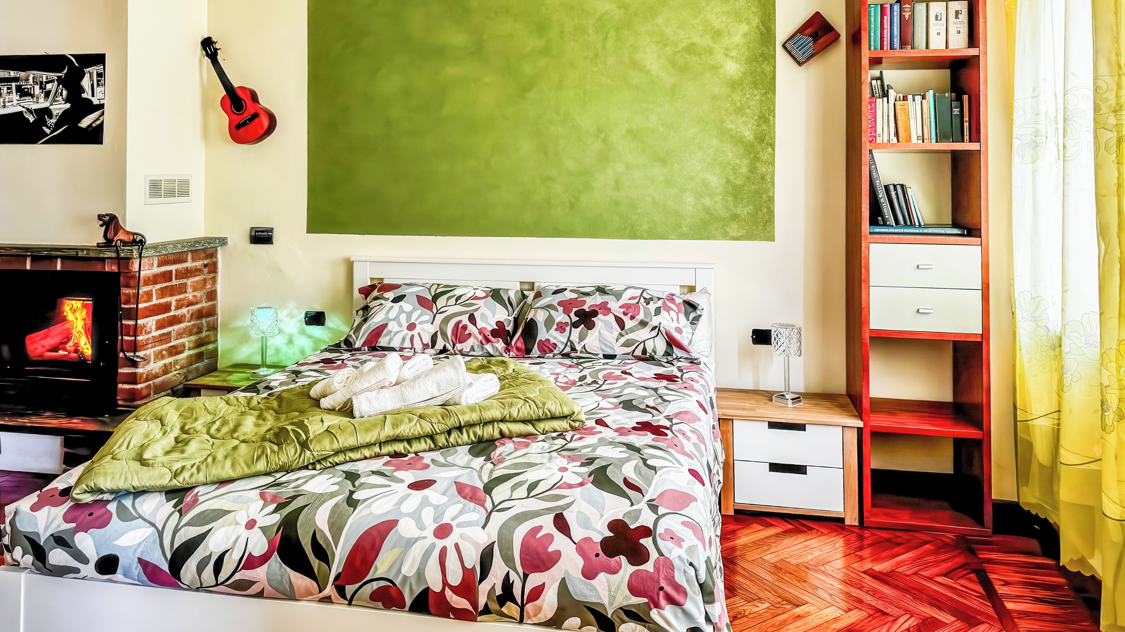 A bedroom with a bed, a bookshelf, a guitar, a fireplace, and a green wall.