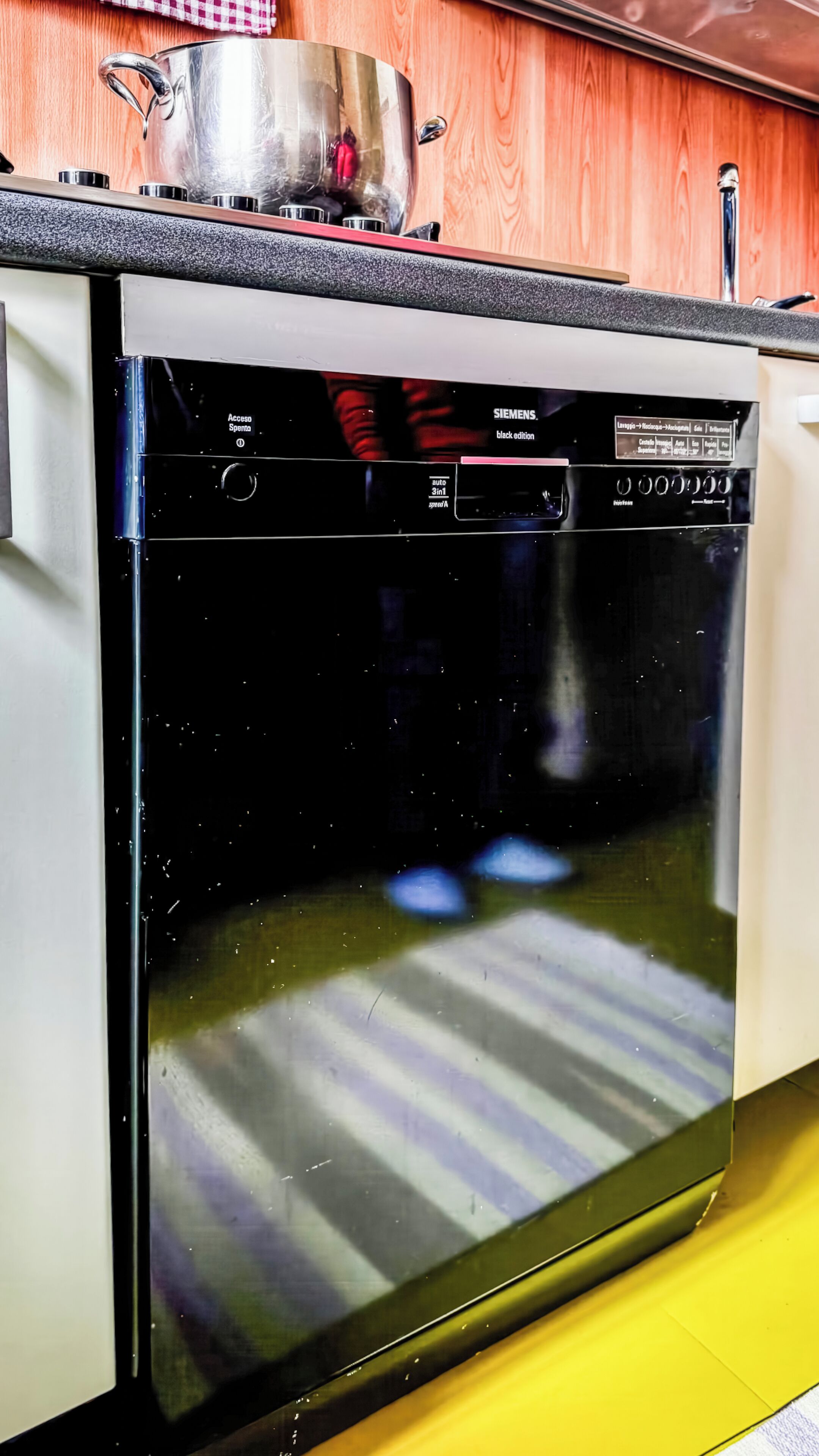 A kitchen with a dishwasher, a stove, and a wooden cabinet.