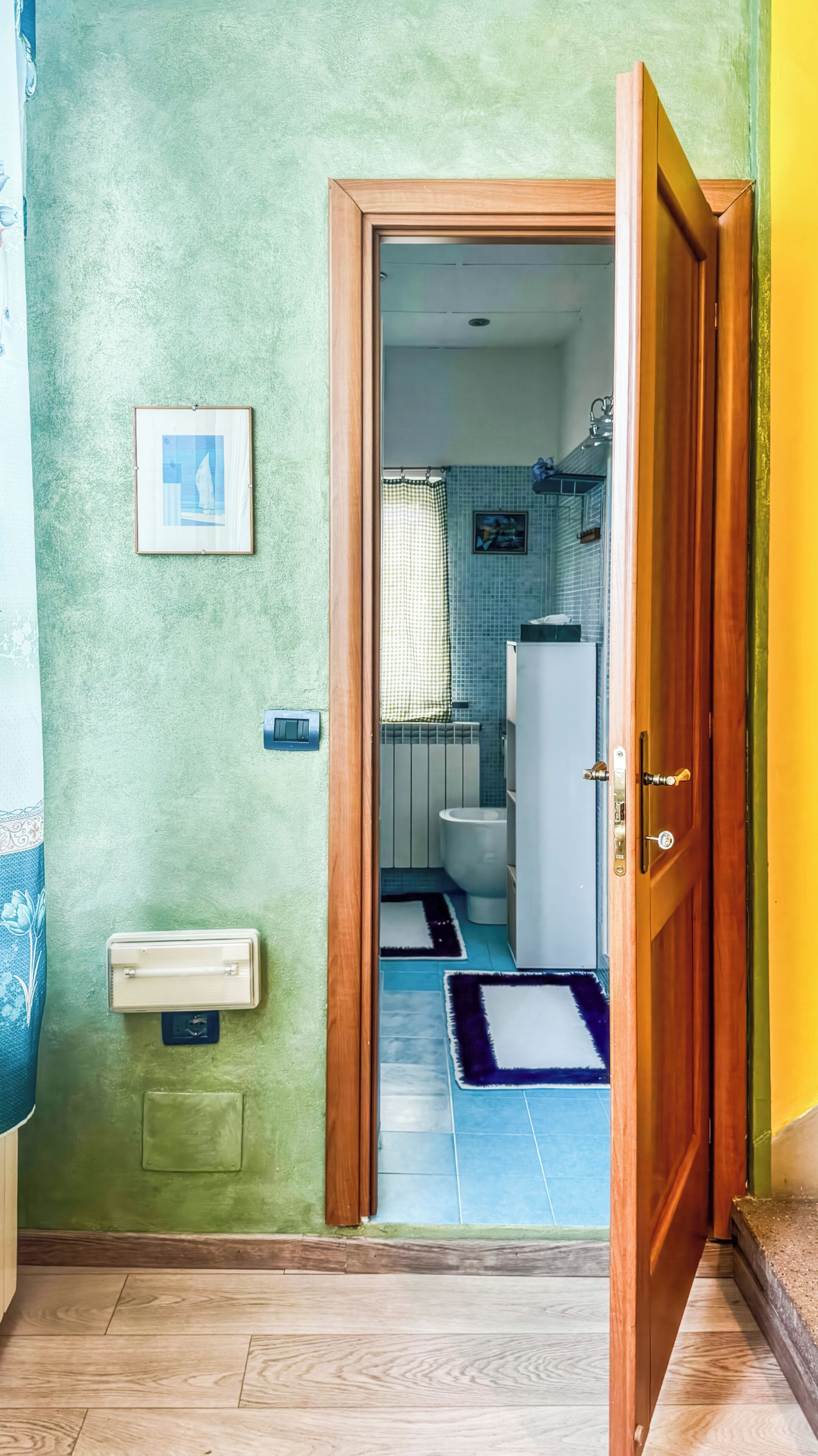 A hallway leading to a bathroom with a toilet, sink, and shower area.