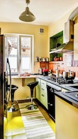 Una cocina con estufa, cafetera y ventana con vista a un edificio tradicional.