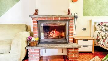 A fireplace with a brick surround, a wooden table, a sofa, and a bed with floral bedding.