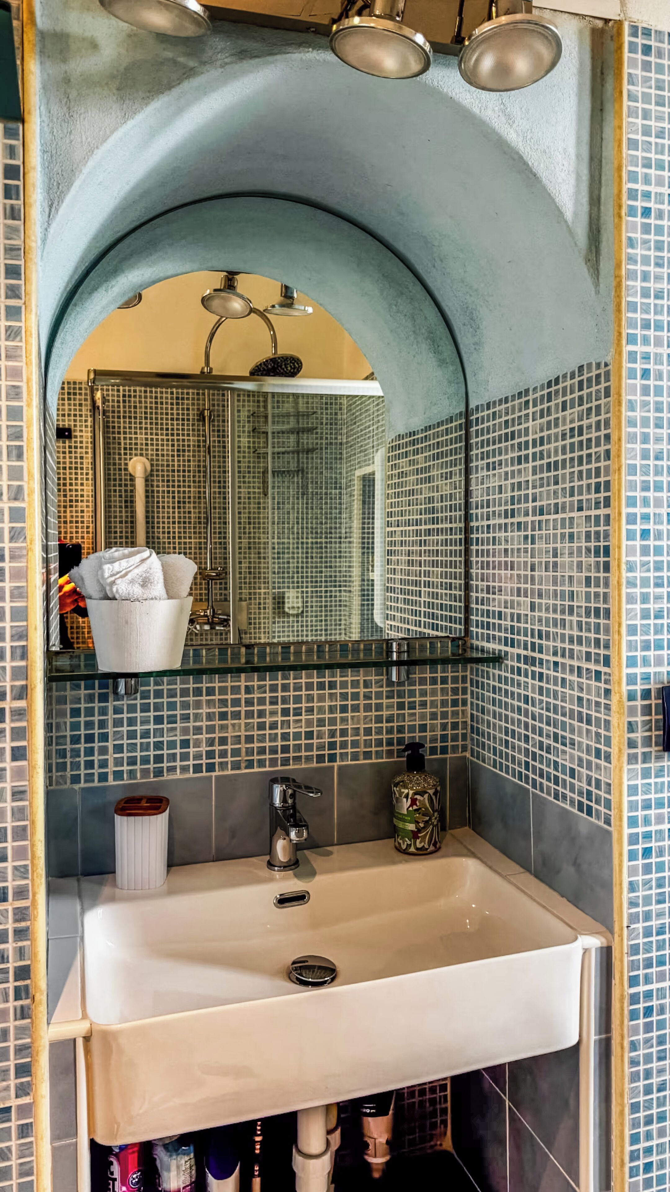 Un baño con lavamanos, espejo y ducha.