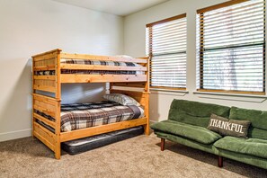 A bunk bed with a mattress at the bottom, a green couch with a pillow, and two windows with blinds. - Forests, Fairways & Lake Fun! Show Low Getaway (Show Low)