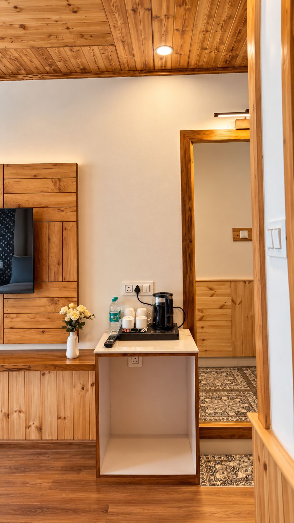 Une chambre d’hôtel avec un plafond en bois, une petite table avec une machine à café, un vase de fleurs et un lit.