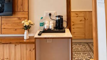 Une chambre d’hôtel avec un plafond en bois, une petite table avec une machine à café, un vase de fleurs et un lit.