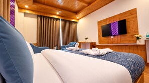 A hotel room with a bed, two chairs, a TV, and wooden paneling. - Hotel Rudra Grand (Manali)