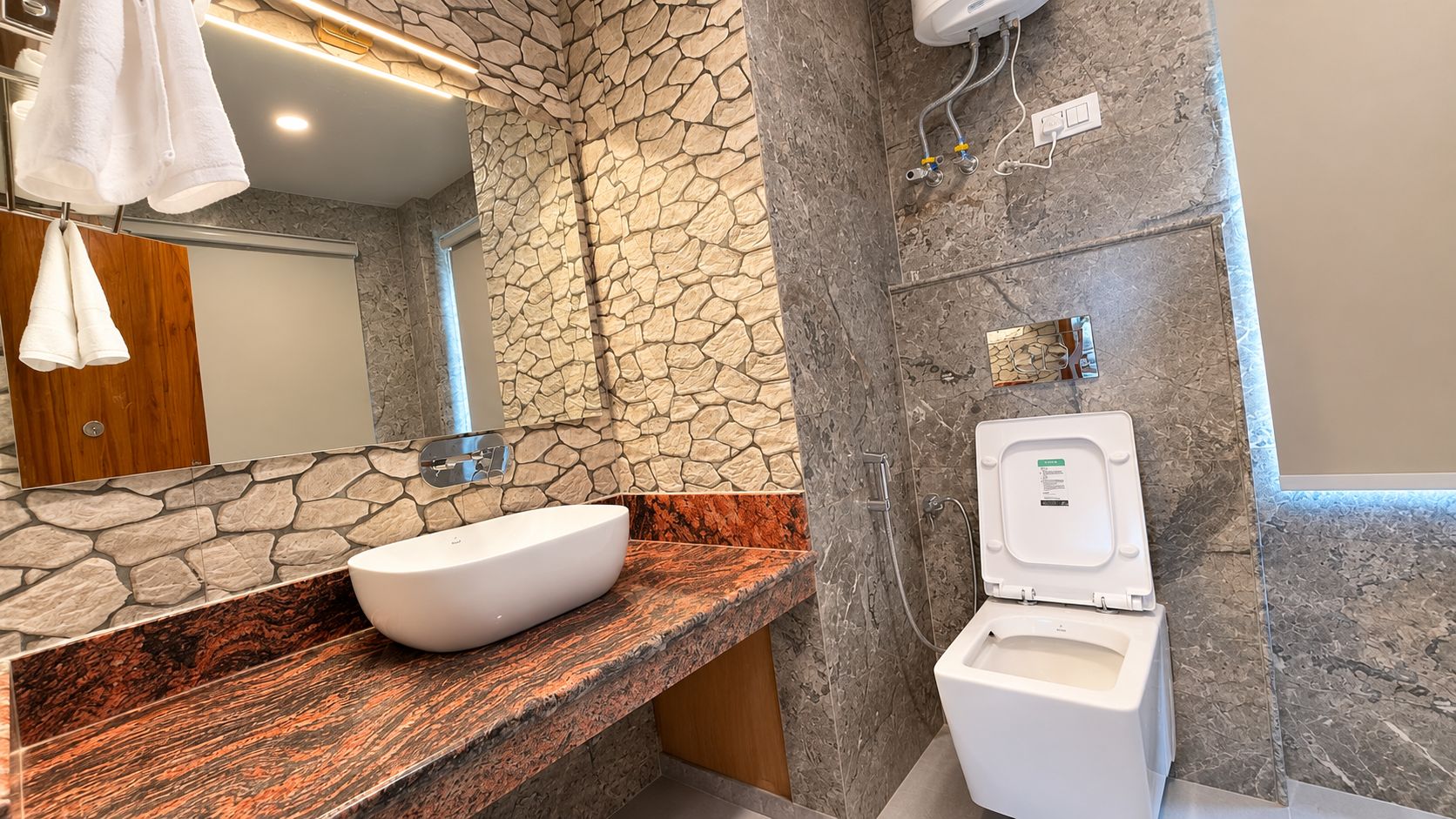 A bathroom with a stone wall, a white sink, and a toilet.