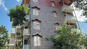 Un edificio de varios pisos con balcones, fachada de piedra y cielo azul despejado.