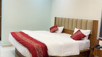Ett hotellrum med en säng, en takfläkt, en luftkonditioneringsanläggning, ett sängbord med en telefon och ett litet bord.