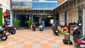 A hotel entrance with a checkered floor, motorcycles parked outside, and a sign for 'ROYAL & BANQUETS'.