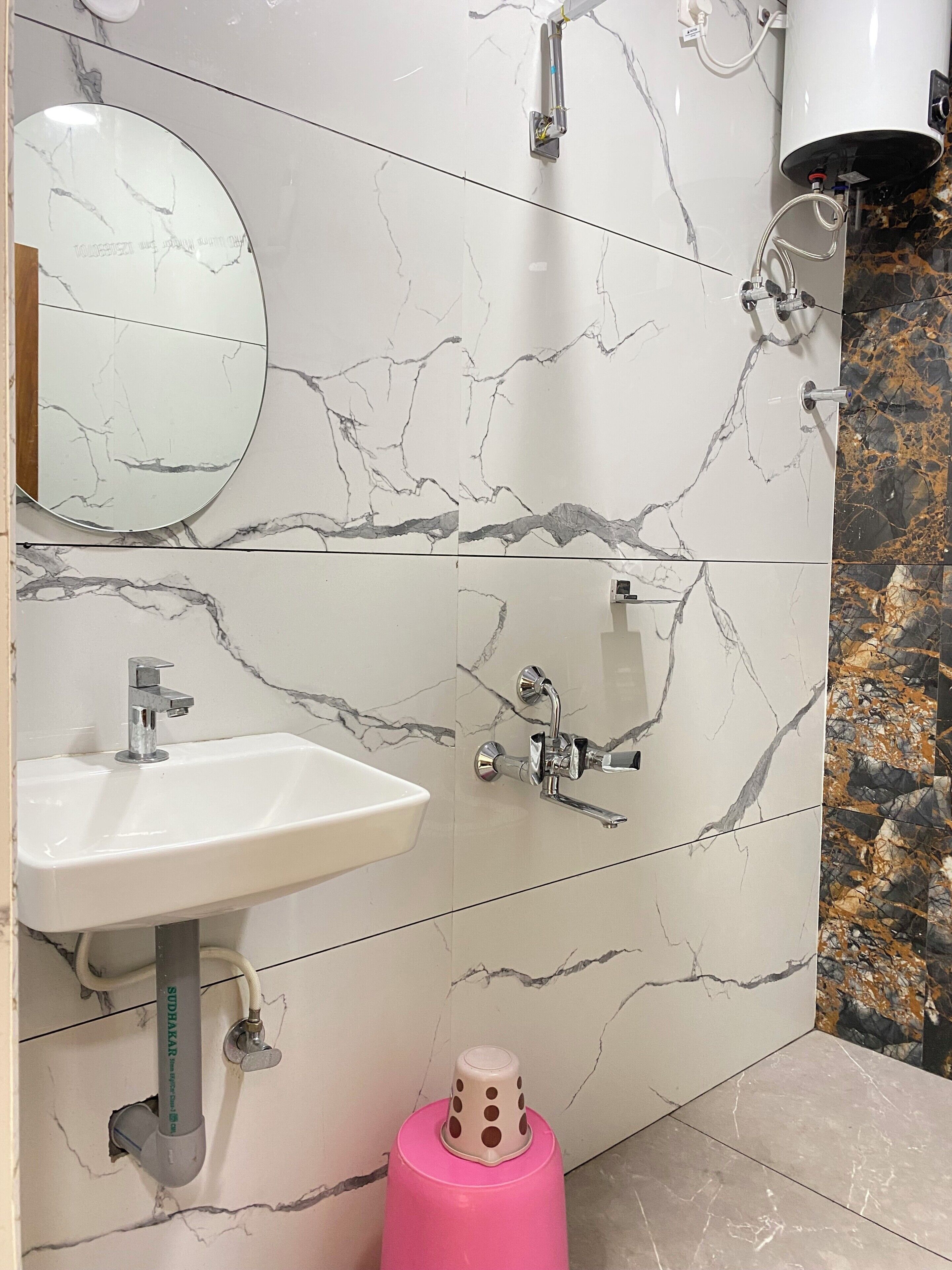A bathroom with a white sink, a mirror, and a shower with a handheld showerhead.