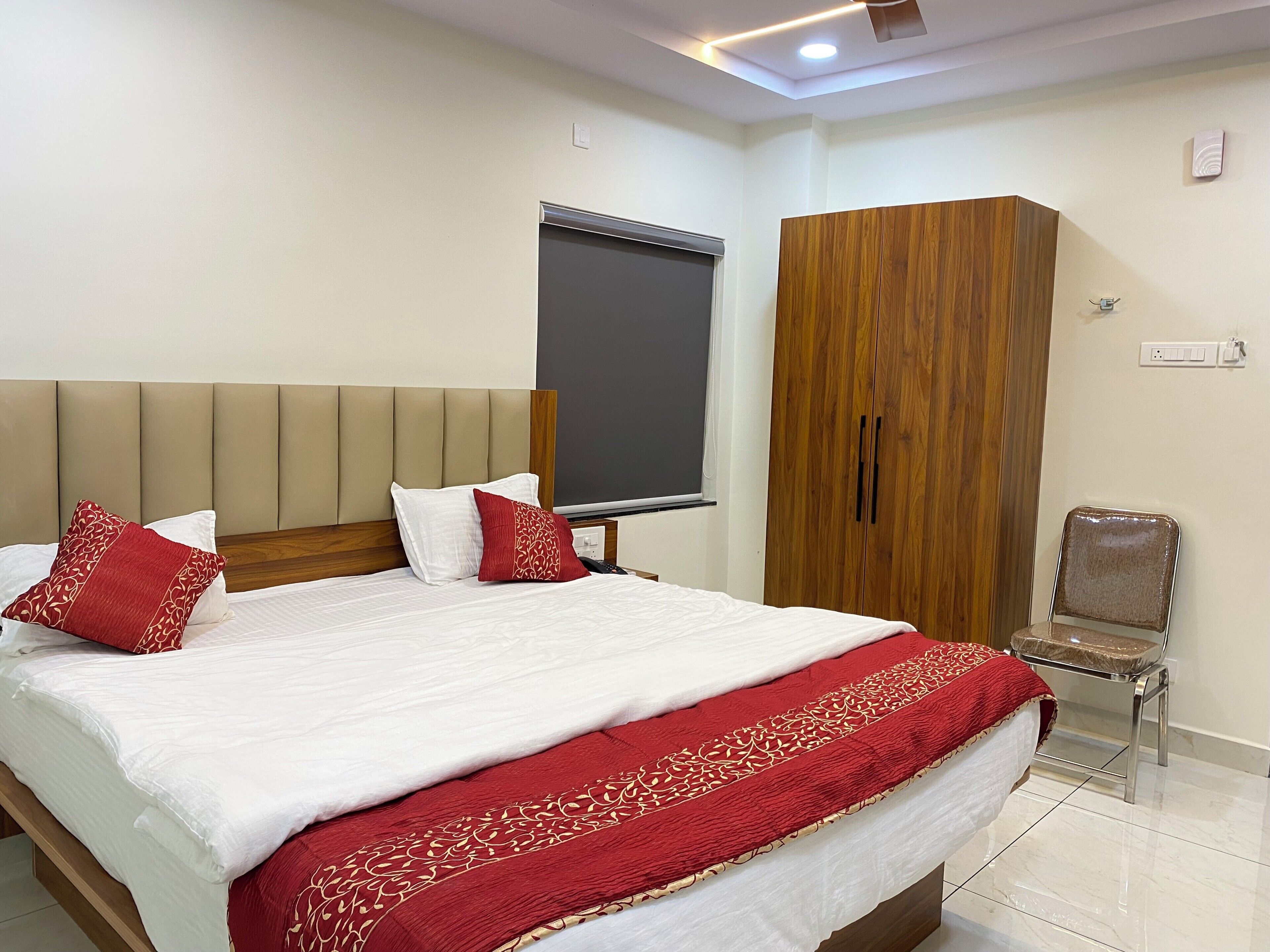 Habitación de hotel con una cama grande, un armario, una silla y una ventana.