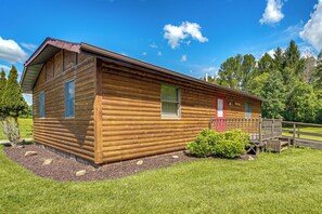 Eine Blockhütte mit roter Tür, einer Veranda und einer kleinen Terrasse.
