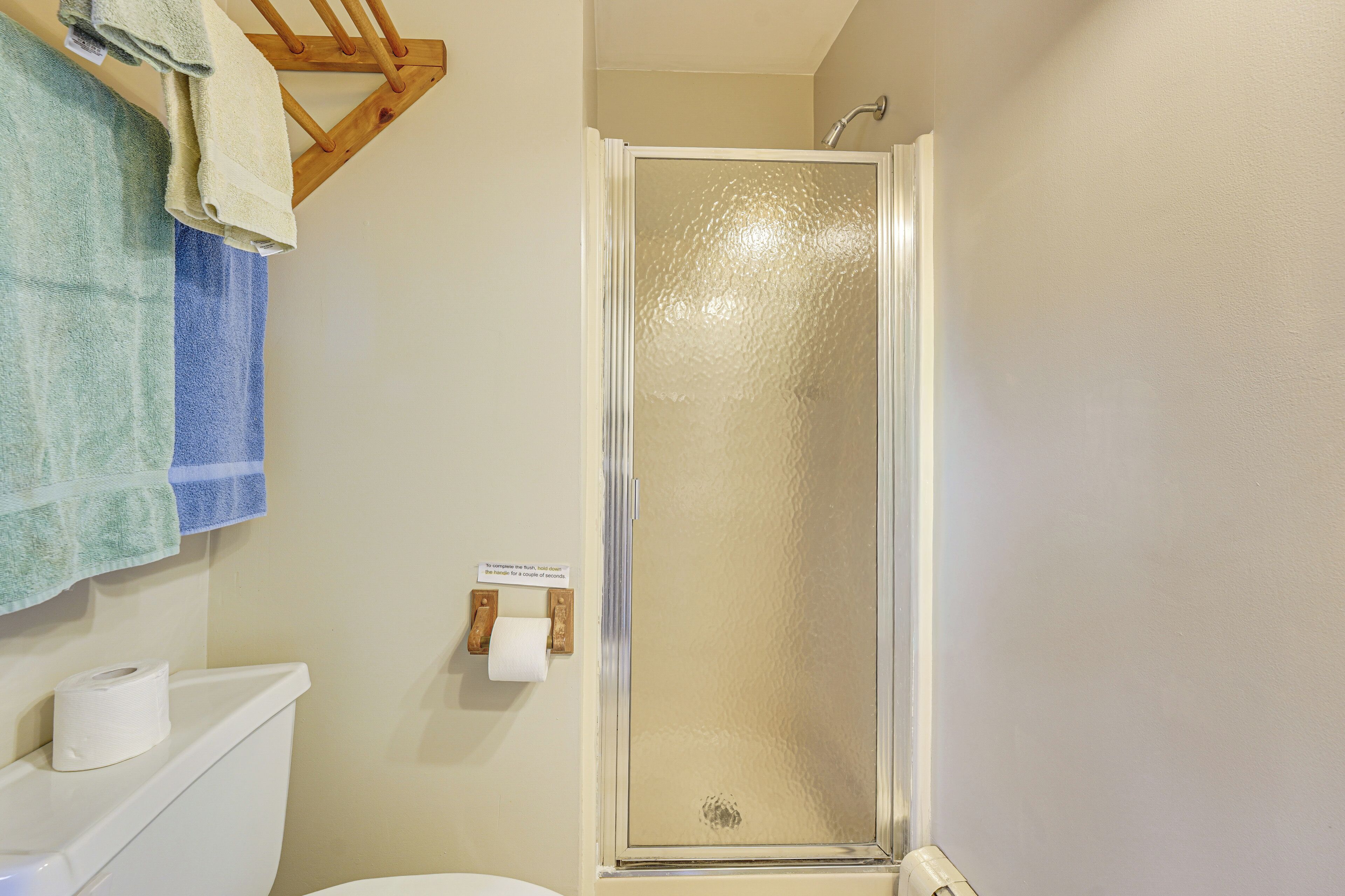 A bathroom with a shower, toilet, and towel rack.