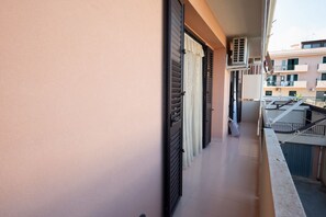 A balcony with closed shutters, a tiled floor, and a view of neighboring buildings. - Cozy apartment of about 90 sqm, able to accommodate up to 4 guests, located on the first floor of a modern building with an elevator. The property is situated in a residential area of ​​Pozzallo—a seaside town whose beaches have repeatedly been awa (Pozzallo)