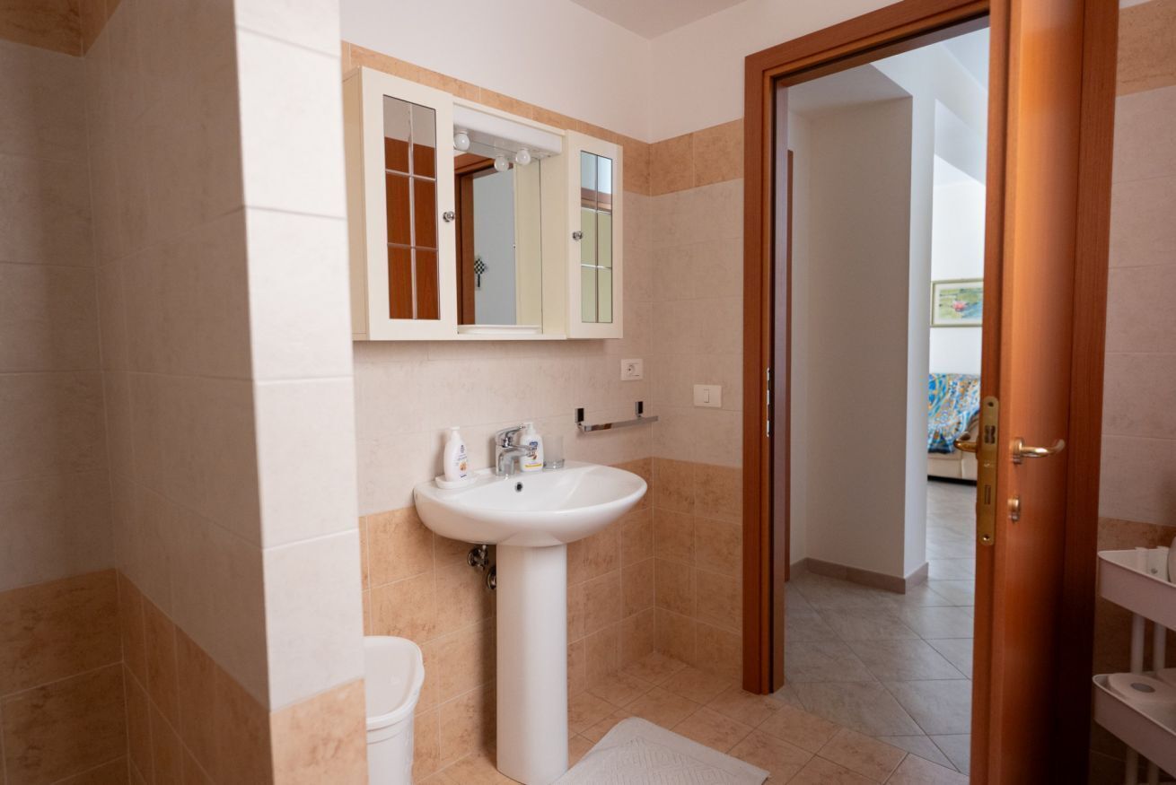 Un bagno con lavandino, specchio e water.