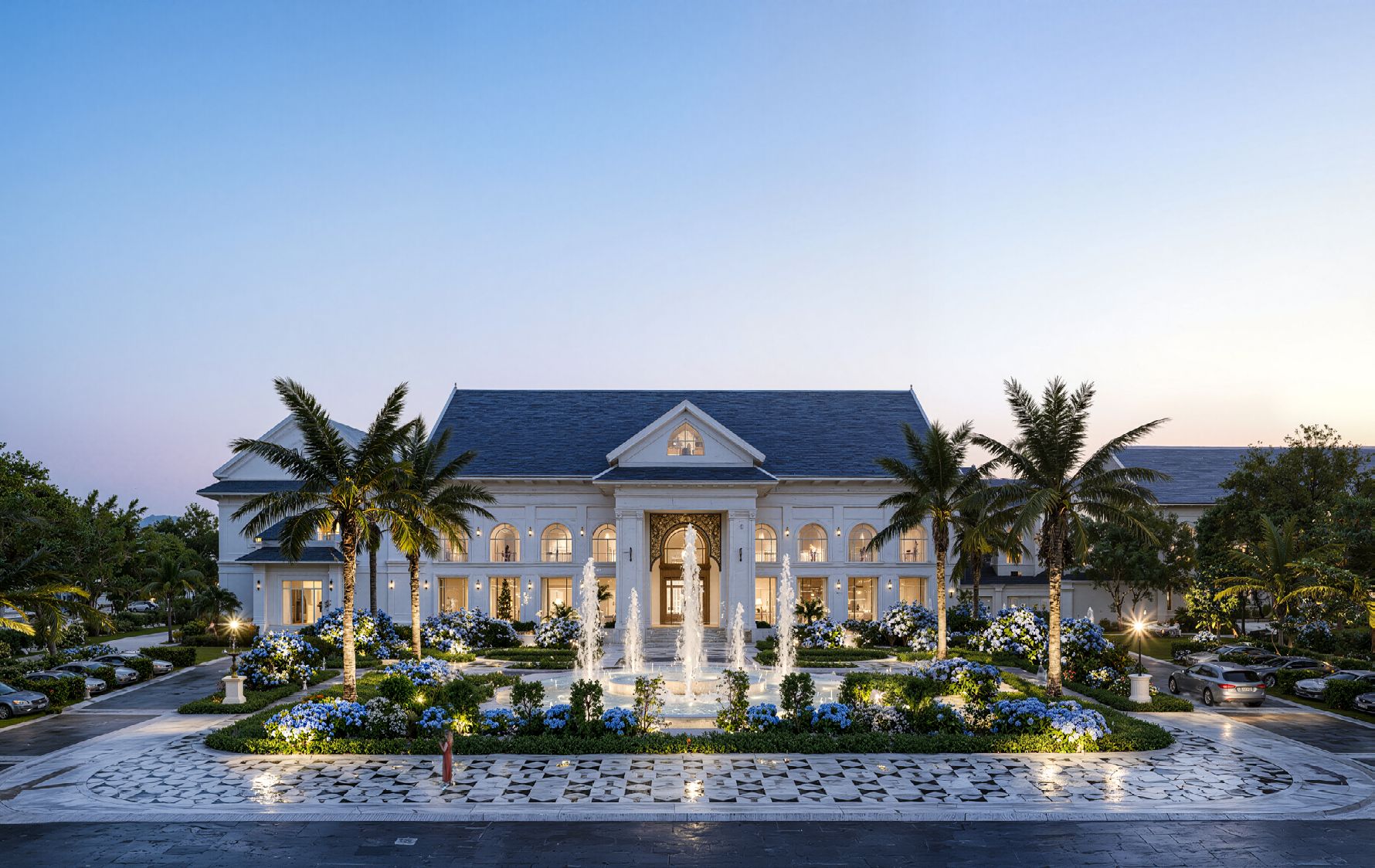 A large, white building with a symmetrical facade, a central entrance, and a fountain in the front garden.