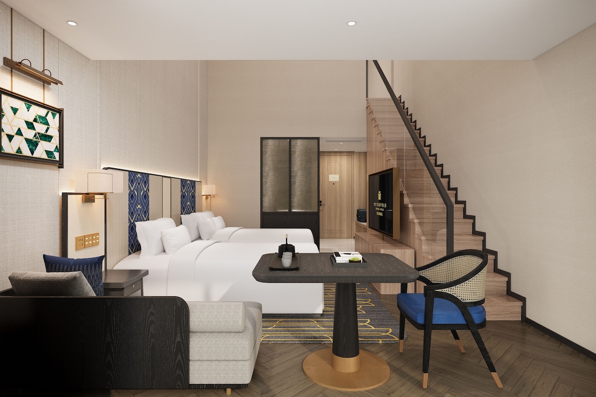 Ein Hotelzimmer mit Bett, Schreibtisch, Stuhl, Sofa, einer Treppe und einem Fernseher.