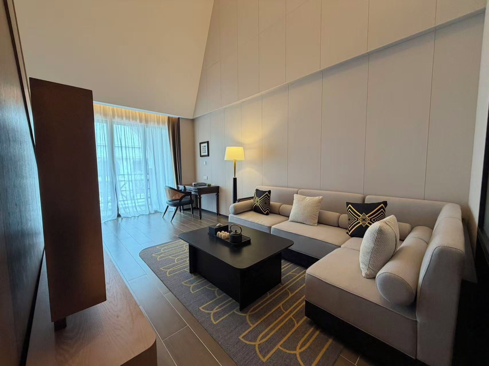 Une chambre d’hôtel moderne équipée d’un canapé, d’une table basse et d’un bureau avec une lampe.
