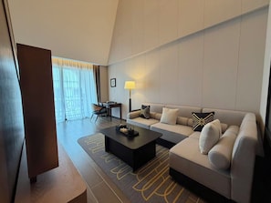 A modern hotel room with a sofa, coffee table, and a desk with a lamp. - Metropolo Jinjiang Hotels Luang Prabang (Luang Prabang)