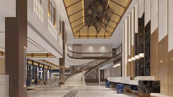 A spacious lobby with a central staircase, high ceilings, and modern lighting fixtures.