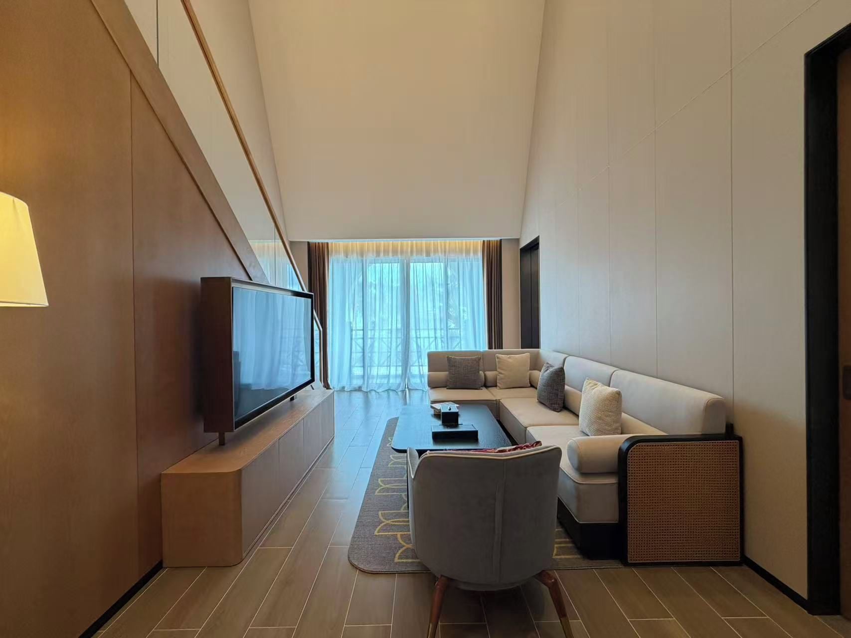 A modern living room with a flat-screen TV, a sofa, a coffee table, and a chair.