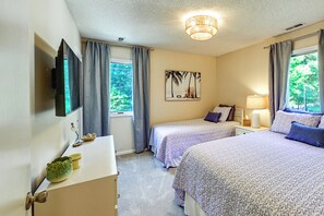 A bedroom with two beds, a flat-screen TV, a painting, and a window with curtains. - Amazing Location! Updated Bethany Beach Retreat! (Bethany Beach)