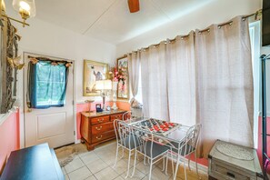 Une pièce comprenant une table à manger, des chaises, une commode, un miroir et une fenêtre avec des rideaux.