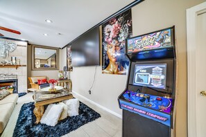 Un salon doté d’un grand téléviseur à écran plat, d’une console de jeux et d’une cheminée.
