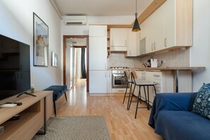 Eine moderne Küche mit weißen Schränken, einem Herd und einer Essecke mit blauem Sofa und Stühlen.