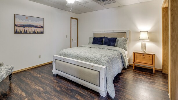 A bedroom with a bed, a nightstand, a ceiling fan, a painting, and a door. - 8 Mi to Nat'l Military Park: Rural Pea Ridge Base (Pea Ridge)