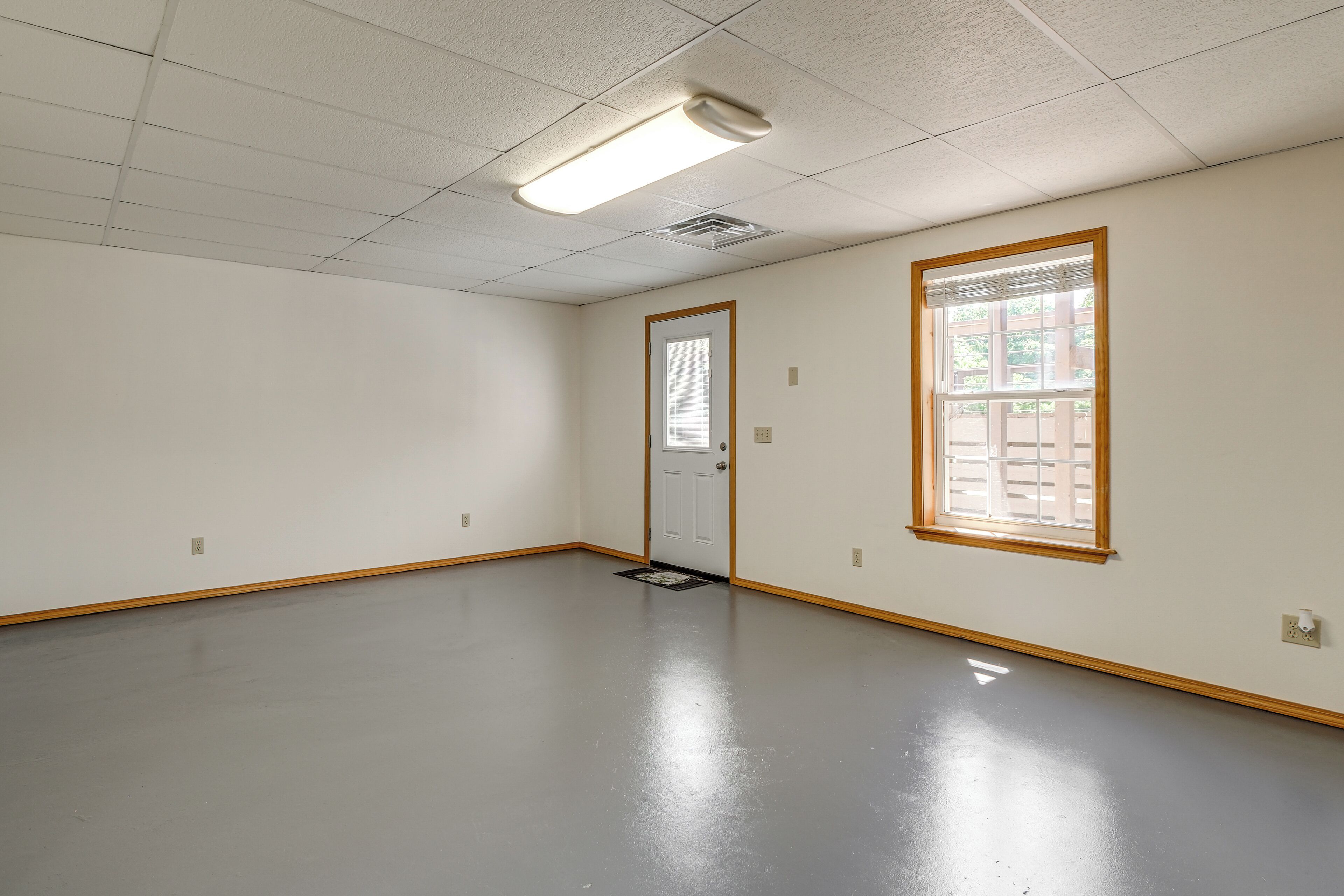 A room with a door, a window, a light fixture, and a floor.