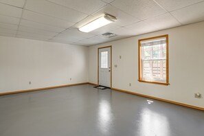 Ein Zimmer mit Tür, Fenster, einer Lampe und einem Boden.