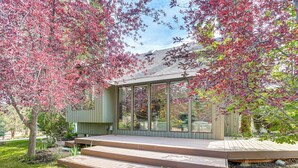 A modern house with a glass facade, wooden deck, and a garden with red-leaved trees. - Fire Pit & Wildlife Views! Tranquil Bend Retreat (Bend)