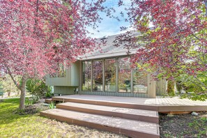 A modern house with a glass facade, wooden deck, and a garden with red-leaved trees. - Fire Pit & Wildlife Views! Tranquil Bend Retreat (Bend)