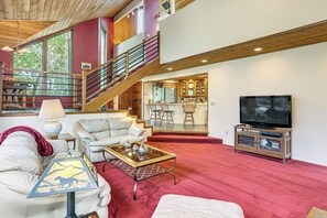 Ein geräumiges Wohnzimmer mit Treppe, Fernseher und Küchenzeile.