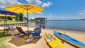 A beach with lounge chairs, kayaks, and a pier extending into the water. - Modern Lake House with Beautiful Shoreline (Frankston)
