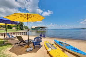 A beach with lounge chairs, kayaks, and a pier extending into the water. - Modern Lake House with Beautiful Shoreline (Frankston)